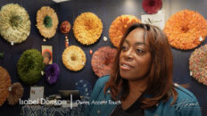 image of Accent Touch owner Isabel Domkam, a black woman, with traditional headdress Juju hats in background
