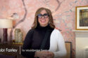 image of interior designer Tobi Farley in black and white dress with big black rimmed glasses, background has pink floral wallpaper . Text: Tobi Fairley for Woodbridge Furniture