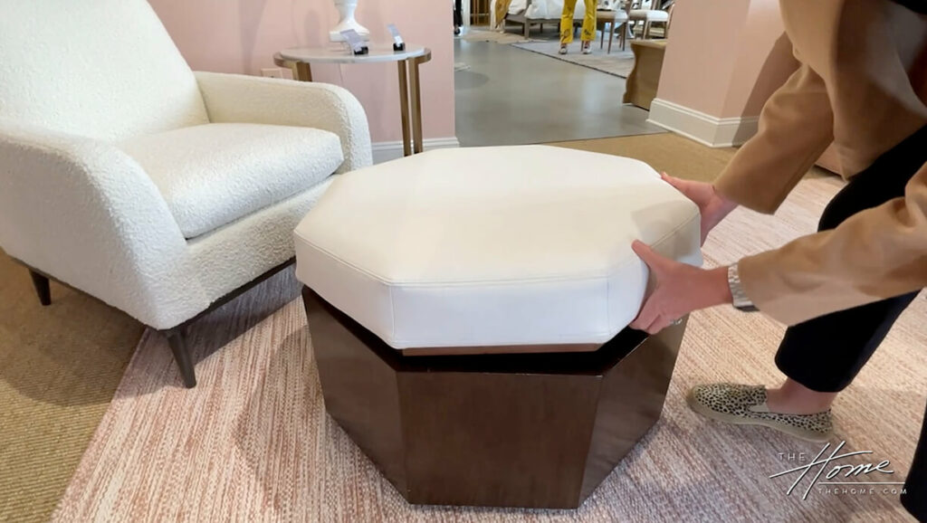 image of dark octagon wood ottoman with white upholstered top lid, person opens lid demonstrating storage inside ottoman
