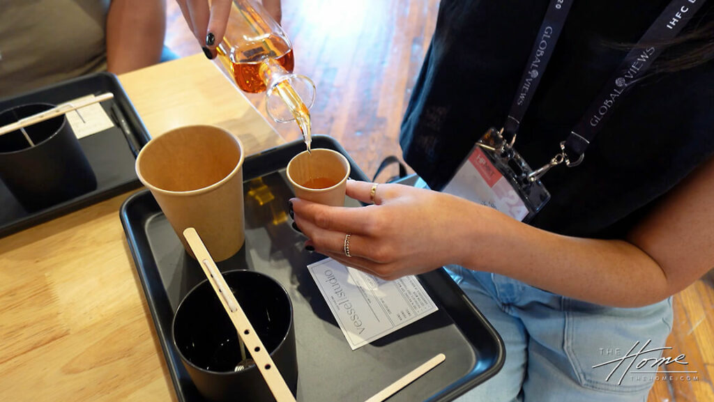 birds eye view of person holding small cup and pouring fragrance inside with Vessel Studio label on a black tray