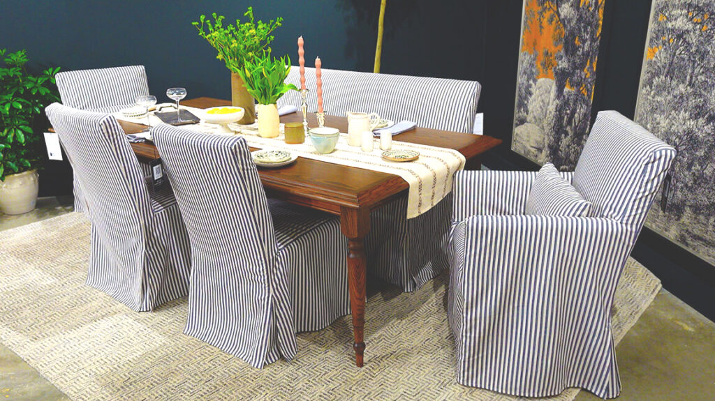 image of dining table set with dishes and blue pinstriped slipcover chairs on a cream rug