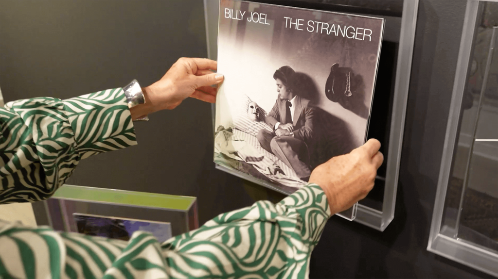 image of arms in green stripe shirt reaching for a record album inside a clear acrylic frame