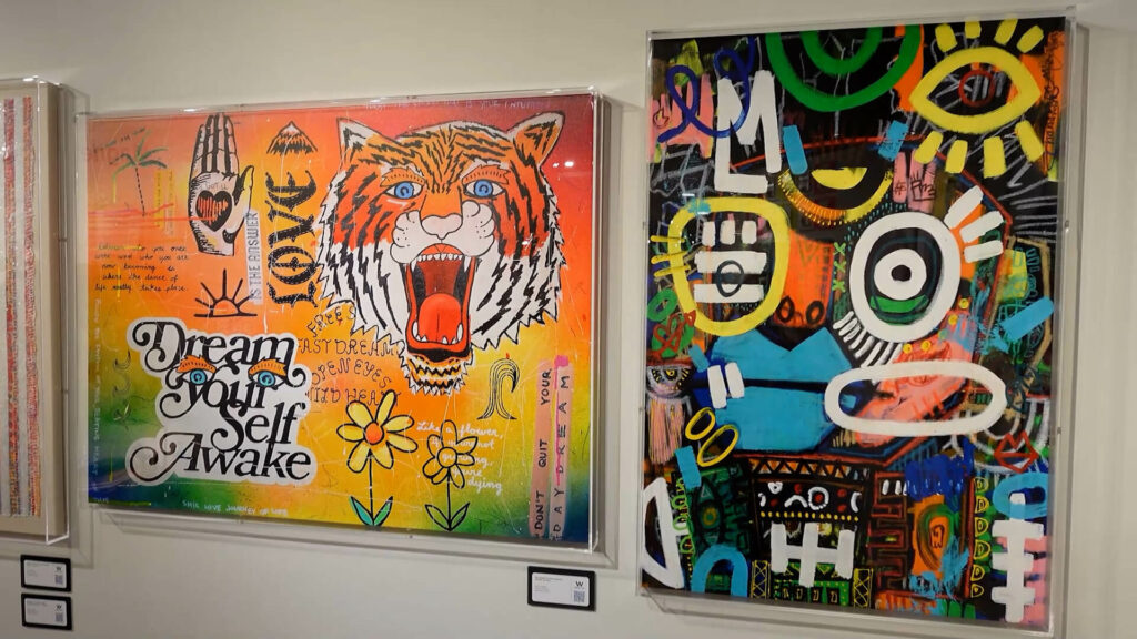 image of wall with 2 colorful original art pieces, 1 with a tiger, 1 with colorful symbols