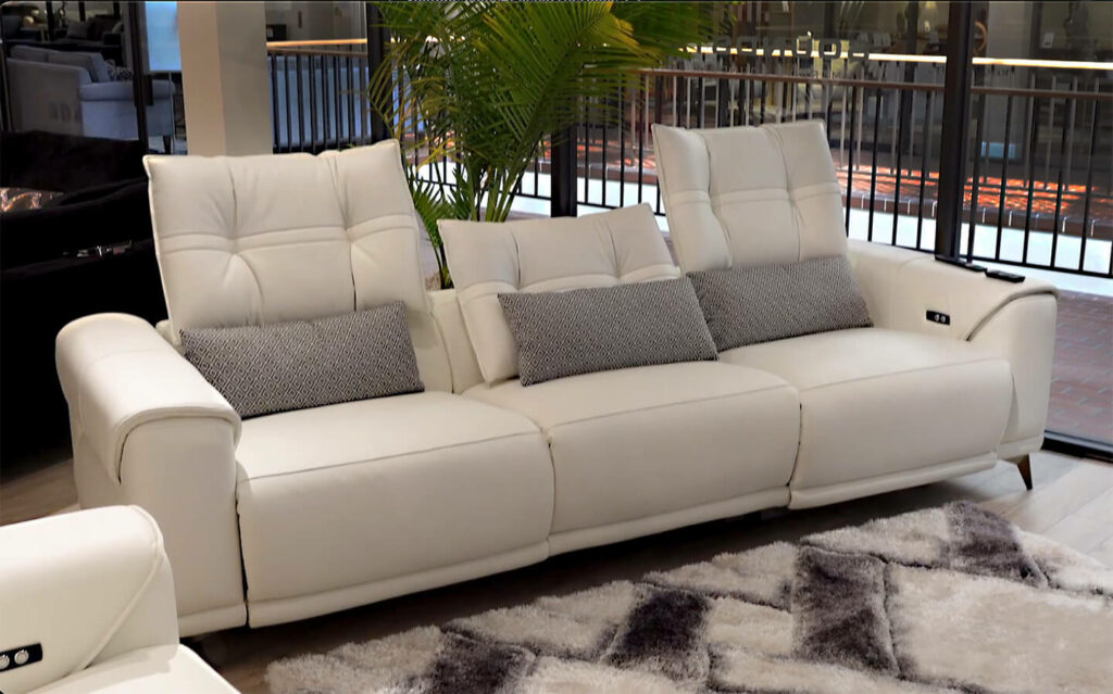 image of cream leather sofa with gray pillows in room with patterned carpet