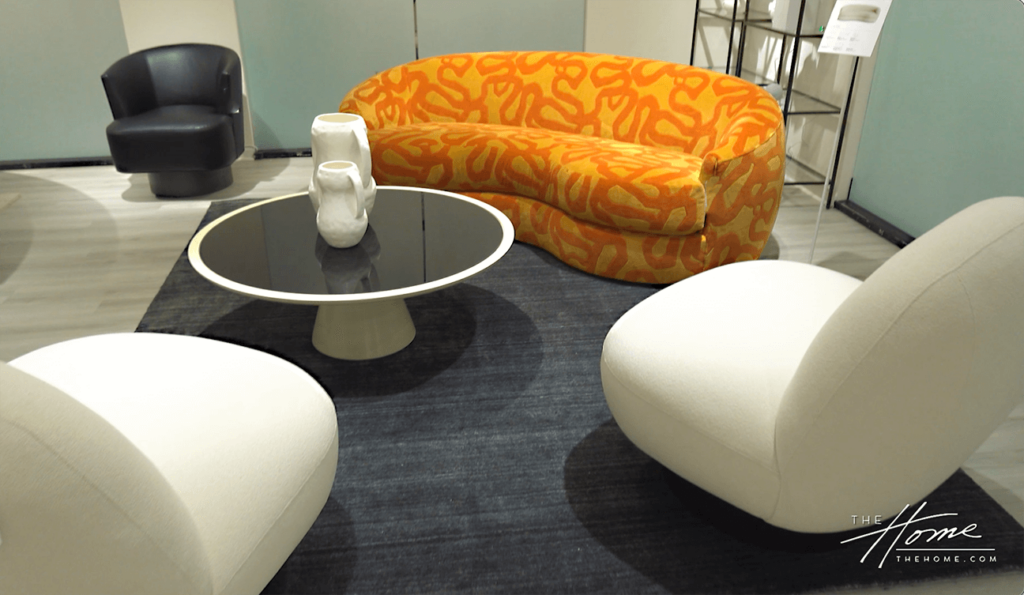 image of bright orange rounded modern sofa with 2 side white round blog shaped chairs, black round coffee table and black side chair