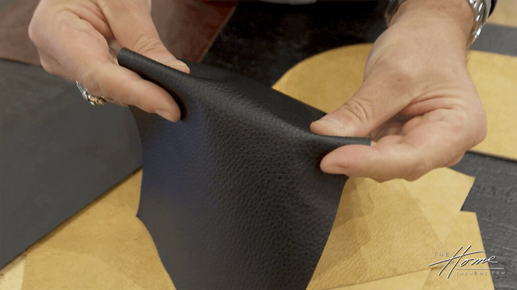 Image: man's hands folding piece of black leather