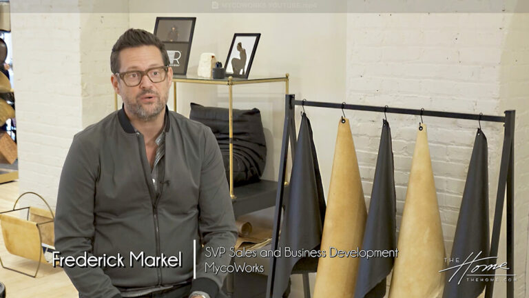 Image: man in gray zip sweater sitting next to rack of black and tan leather alternative samples