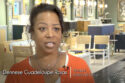 Image: black woman in orange sweater in showroom of home furnishings. text: Dennese Guadeloupe Rojas, Principal, Interiors By Design