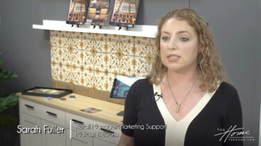 Image: woman in black and white dress in front of art tiles on backsplash in geometric yellow and brown pattern