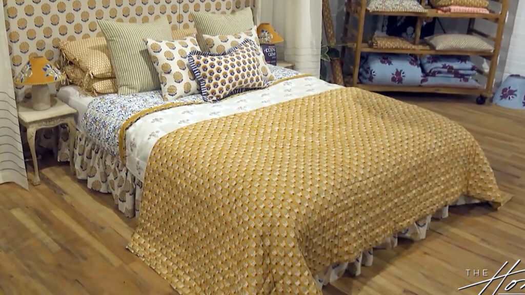 Image: Hand printed Indian textiles bedding set, yellow print bedspread, multiple colored pillows, block print pattern headboard on wood floor