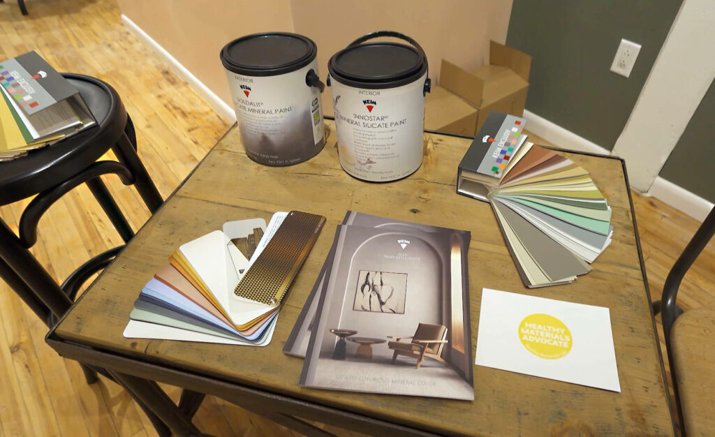 Image: wood table with 2 gallon paint cans, several paint color swatch books and brochures