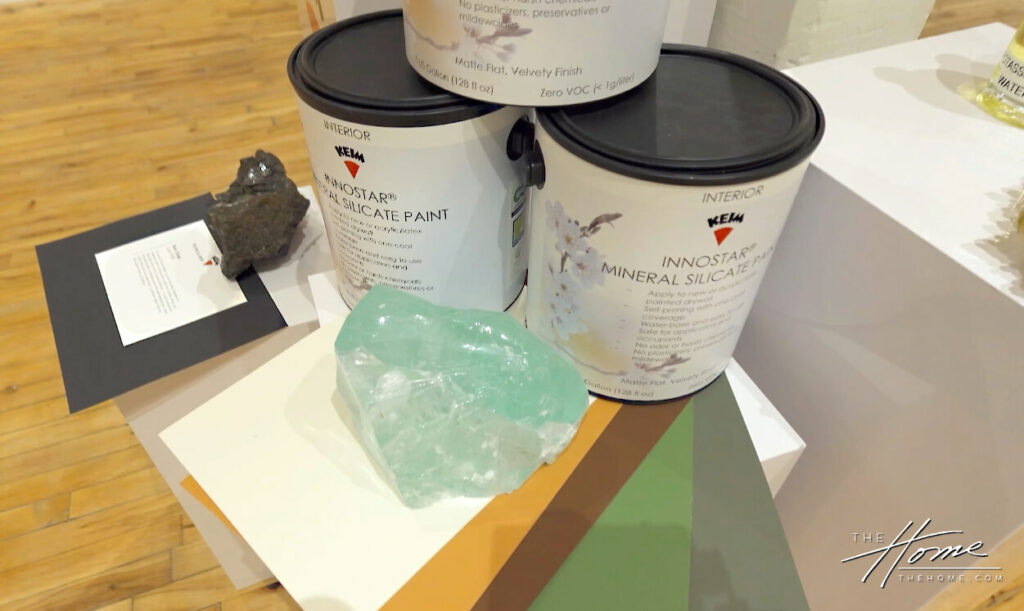 Image: 3 gallon cans of wall paint Keim brand, large blue-green translucent crystal rock, paint swatches on table