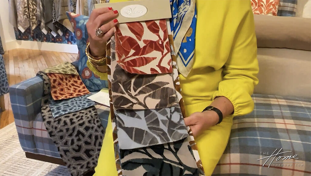 Denise McGaha in yellow dress showing Pindo pattern velvet textile fabric swatches in colorful showroom