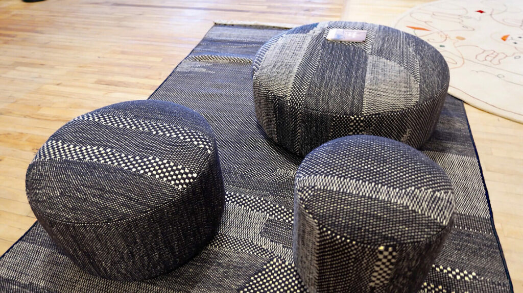 Image: 3 circular poufs on carpet of same material: black and white woven patterns irregular weave
